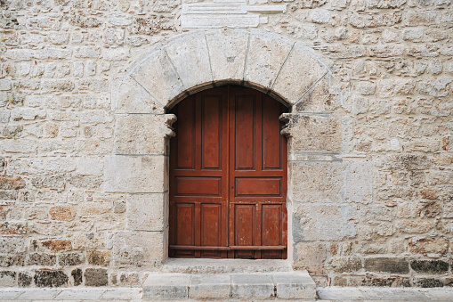 Old massive large wooden door in a stone wall of a church.