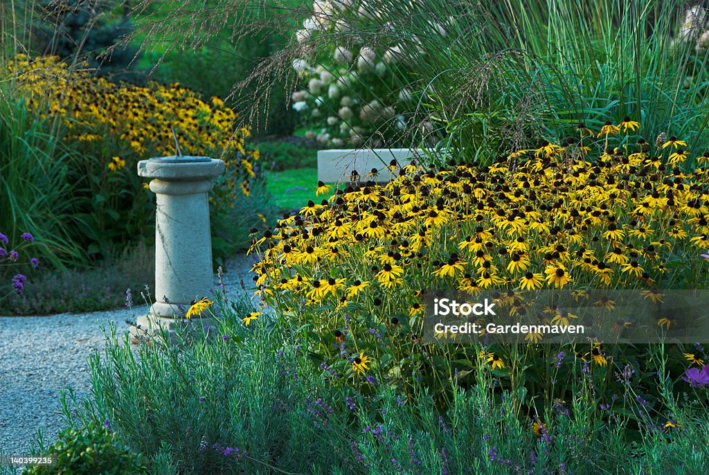 Late Summer Garden Garden scene with sundial in late summer with black-eyed Susan flowers, evening light Bench Stock Photo