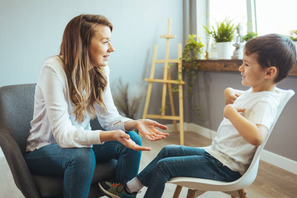 Child counselor during psychotherapy session Cheerful young kid talking with helpful child counselor during psychotherapy session in children mental health center. Child counselor during psychotherapy session obsessive stock pictures, royalty-free photos & images