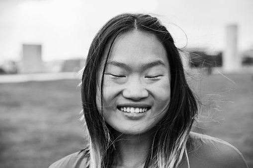 Asian girl smiling on camera at city park - Focus on face - Black and white editing