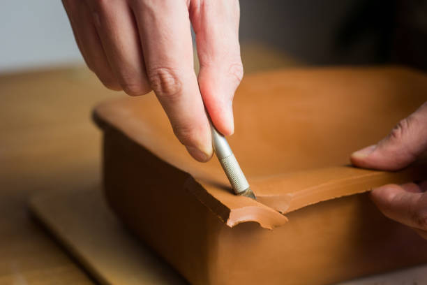 istock Potter cuting clay. Master working in Pottery studio with raw ceramic roasting dish. Art hobby 1403994848