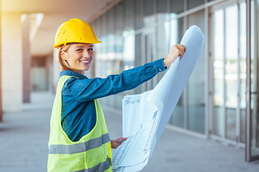 Female architect holding blueprints on construction site
