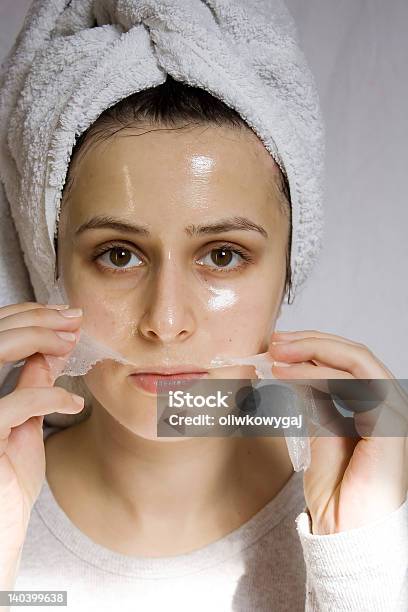 Woman With Towel On Head Peeling Off A Collagen Mask Stock Photo - Download Image Now