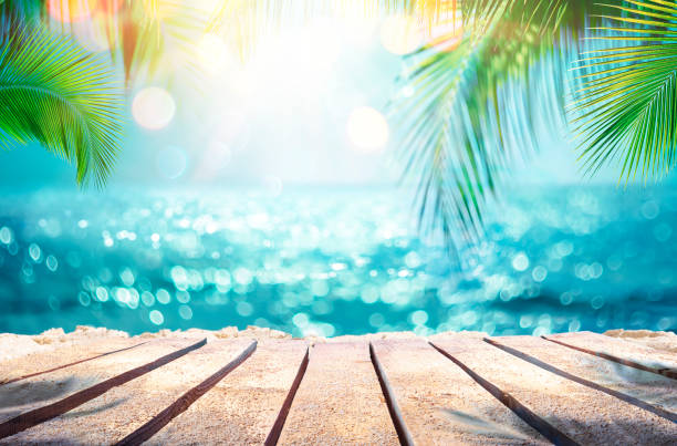 Summer Table And Sea With  Blurred Leaves Palm And Defocused Bokeh Light On Ocean - Wooden Plank In Abstract Landscape stock photo