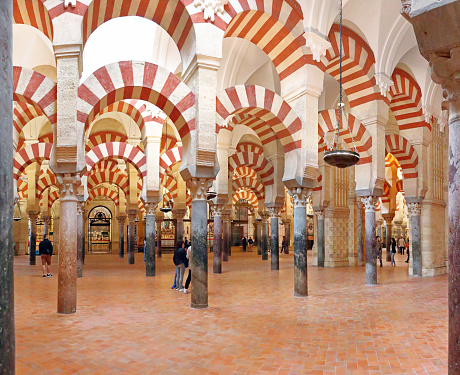 Scattered tourist under the dazzling Arabic arches in the interior of the Mesquita of Cordoba, Andalusia, Spain