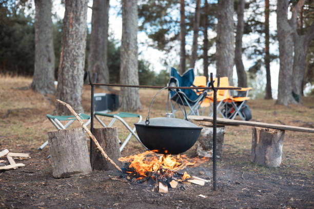 istock Cooking in cauldron on open fire in nature. Bowler on bonfire in forest. Pot from cast iron on campfire on background of river. Copy space. 1403998035