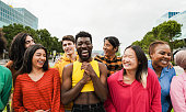 Young diverse people having fun outdoor laughing together - Focus on asian man face