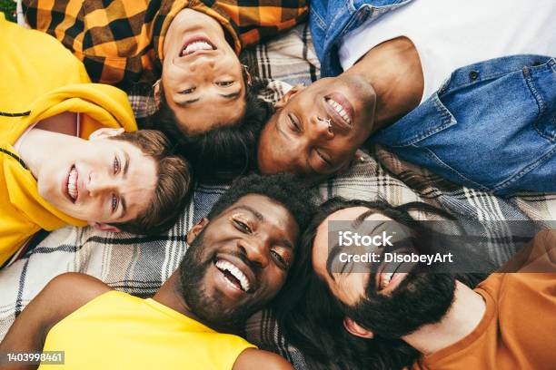 Happy Diverse Male Friends Having Fun Lying Together In Circle Outdoor Soft Focus On Blond Man Stock Photo - Download Image Now