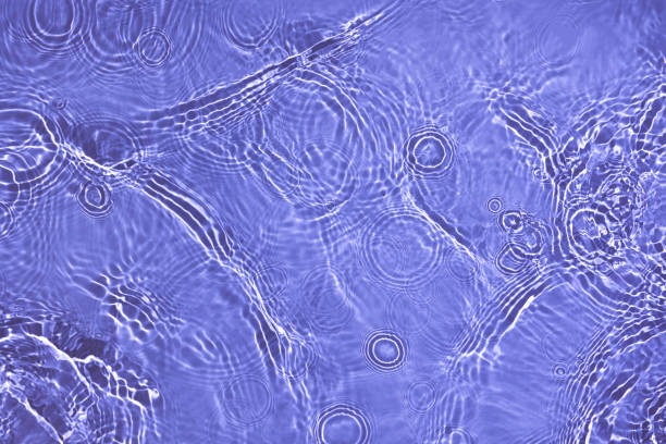 Transparent purple water surface texture with ripples, splashes and bubbles. Abstract nature background Water waves in sunlight with copy space Cosmetic moisturizer micellar toner emulsion. 2022 color