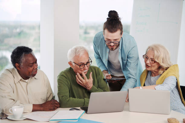 istock A young hipster teacher is explaining to a small group of senior students about laptops and technology. 1403999443