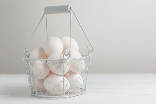 chicken eggs in a white decorative basket on a white background