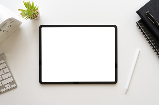 Modern workspace with tablet blank screen mockup surrounded with accessories and stationery on black background. top view, flat lay