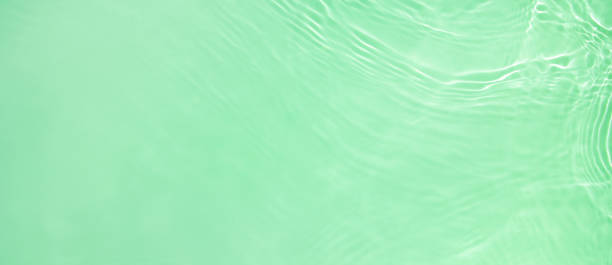 banner background transparent green clear water wave surface texture Abstract summer banner background Transparent green clear water surface texture with ripples and splashes. Water wave in sunlight, copy space, top view Cosmetics moisturizer micellar toner emulsion mint green stock pictures, royalty-free photos & images