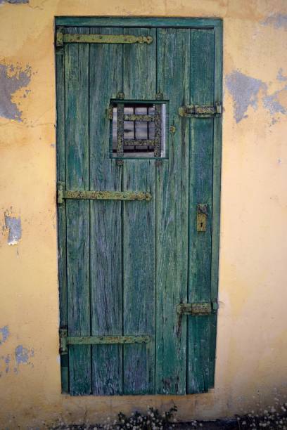 istock Weathered green door with rusty bolts and a yellow wall 1404001752