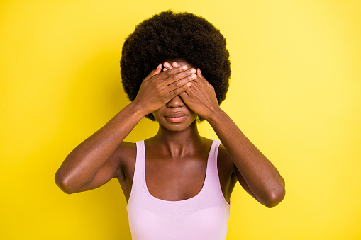 Photo of serious afro american attractive woman cover hands eyes avoid eye contact isolated on vivid yellow color background.