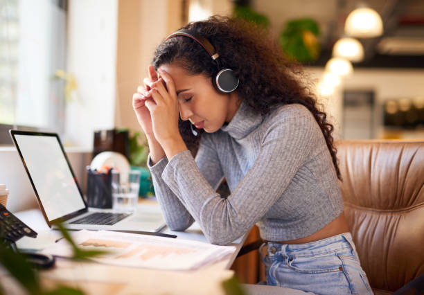 istock Stressed call centre agent sitting at her desk. Young worker sitting in modern office with a serious, thinking expression 1404005946