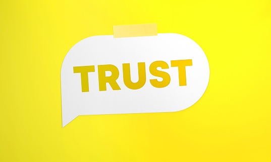 Trust Written White Speech Bubble On Yellow Background. Communication Concept.