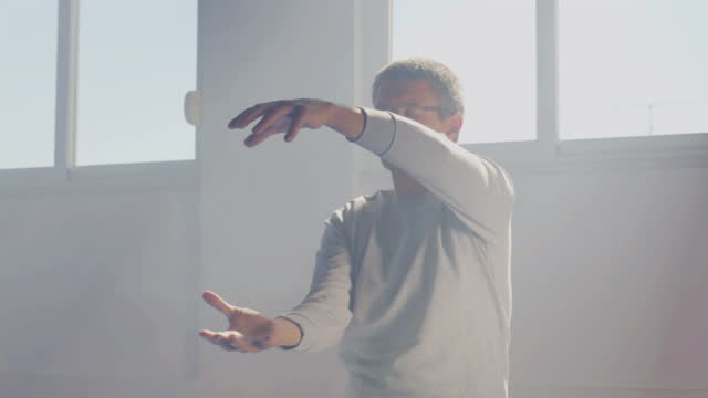 Man practicing tai chi movements with closed eyes