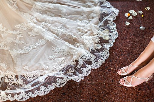 Rose petals on a white wedding dress and the legs of the bridesmaid