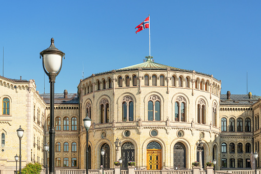 Oslo Parliament (The Storting building or Stortingsbygningen) with Norwegian flag in central Oslo. The building is built in yellow brick.