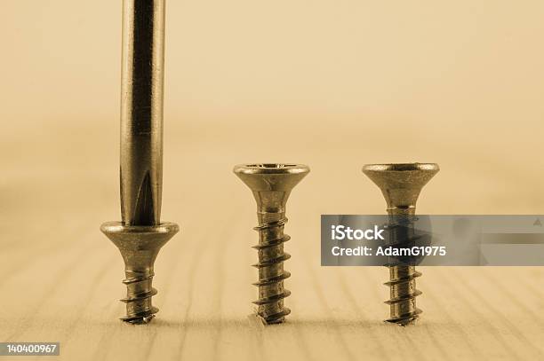 Three Screws In Plank Of Wood With Screwdriver Stock Photo - Download Image Now - Bolt - Fastener, Building - Activity, Chrome