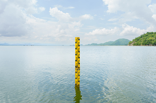 La escala amarilla mide la altura del agua en la presa. El agua en el embalse es abundante y se utiliza para la agricultura y el consumo de la aldea. Reservando la naturaleza acuática en Tailandia photo