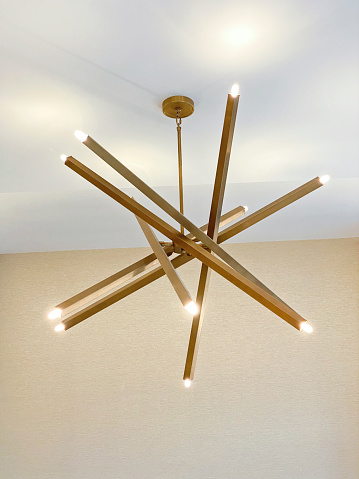 Suspended wooden lamp hanging near white wall in light modern interior