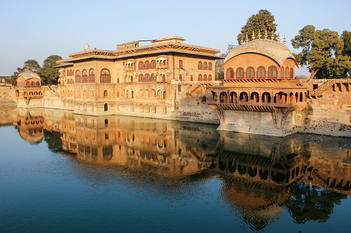The exterior facade of the ancient royal palace rising above the waters of a lake in the town of Deeg.