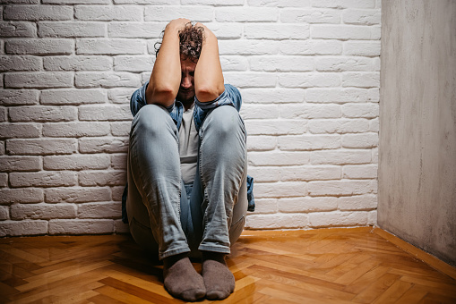 Depressed young man sitting on the floor of the room and contemplating life.