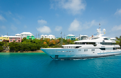 St. George, Bermuda-May 23, 2022 Passengers and crew are seen on the decks of the Netanya 8. Owned by American billionaire and Slim-Fast founder, S. Daniel Abraham this 190' mega yacht  sails past the pastel homes in St. George, Bermuda on a late May afternoon.