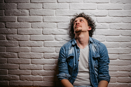 Depressed young man sitting on the floor of the room and contemplating life.