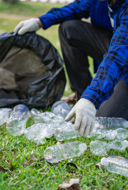 istock A man's hand puts plastic bottles in a black garbage bag to clean in the park. avoid pollution It is environmentally friendly and ecologically clean on Earth Day and can be sold for free income. 1404021406