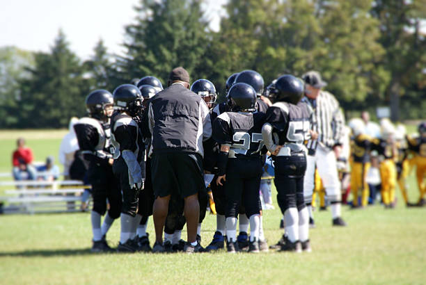 fußball-trainer in der gruppe bilden mit team - child american football football sport stock-fotos und bilder