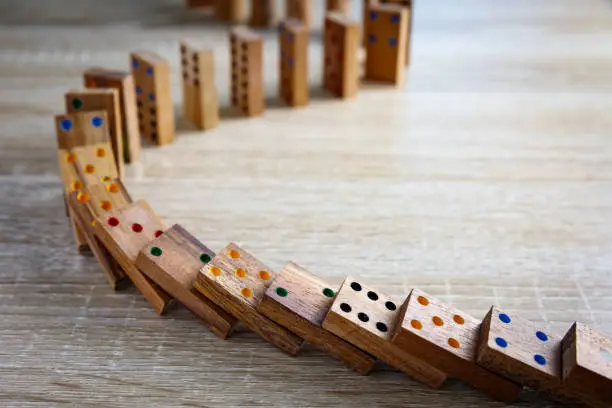 Photo of Domino effect concept with wooden dominoes pieces row falling. Business crisis management, finance intervention, conflict prevention or mistake consequence concept