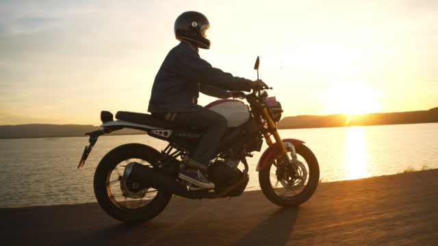 Man riding motorcycle on beach at sunset. Relaxation Holiday