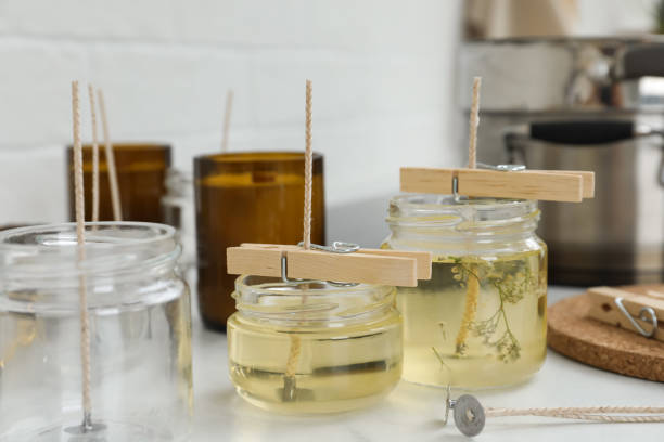 istock Glass jars with melted wax on white table. Handmade candles 1404023645