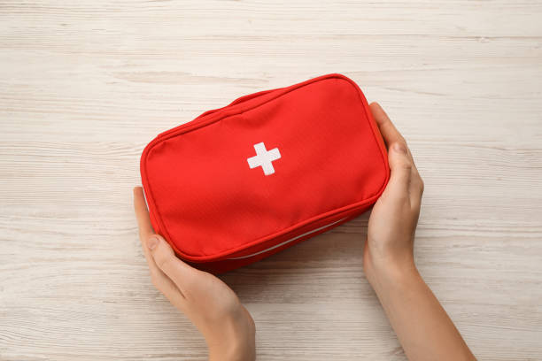 donna che tiene la borsa del kit di pronto soccorso al tavolo di legno bianco, vista dall'alto - travel healthcare and medicine emergency services urgency foto e immagini stock