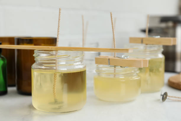 istock Glass jars with melted wax on white table. Handmade candles 1404023700