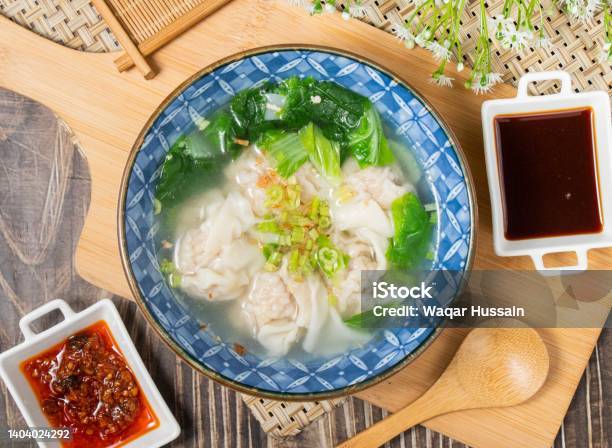Fresh Meat Wonton Soup With Sauce And Spoon In A Plate Isolated On Wooden Cutting Board Top View Stock Photo - Download Image Now