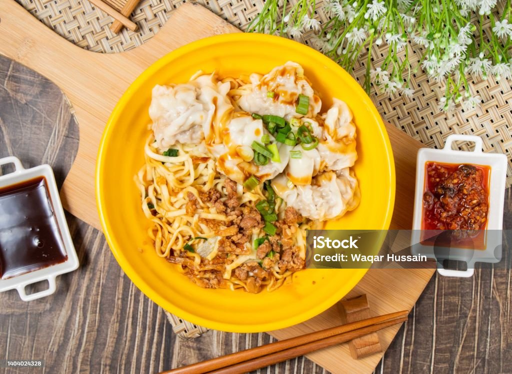 Fresh Meat Wonton Pasta with sauce and chop sticks in a plate isolated on wooden cutting board top view Asia Stock Photo
