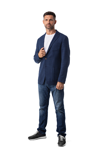 Confident mid adult businessman wearing blazer and jeans and standing on white studio background