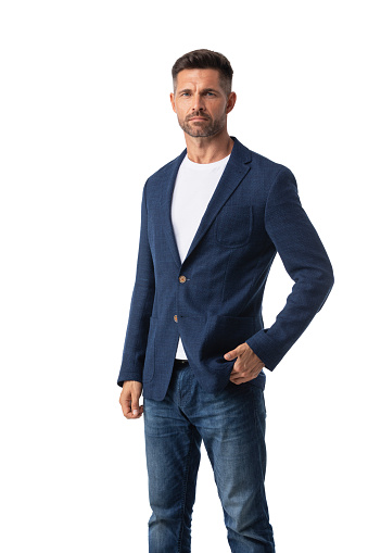 Confident mid adult businessman wearing blazer and jeans and standing on white studio background