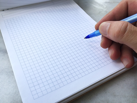 Hand writing on the note pad with pen on the marble texture table