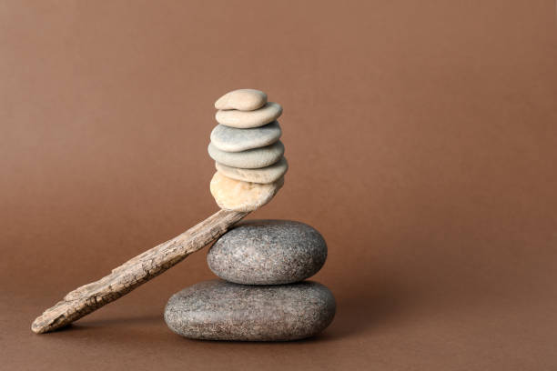 istock Stack of stones balancing on wooden stick against brown background, space for text. Harmony concept 1404028465