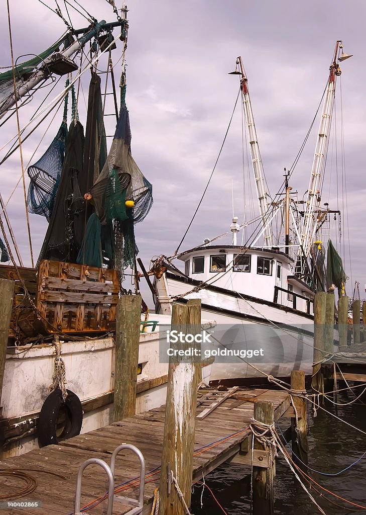 Shrimp Boats Docked At Pier These of two of about ten shrimp boats docked at this Fernandina Beach, Florida pier --- where the modern shrimp boat was invented. Anchored Stock Photo