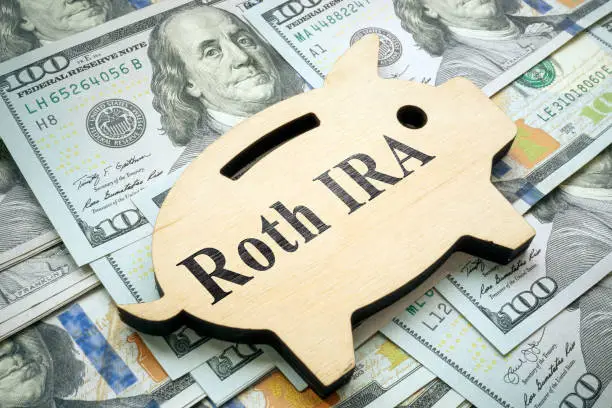 Photo of Piggy bank with sign Roth IRA on money.