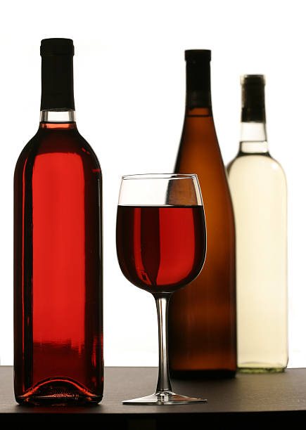 Glass filled with Red Wine and  bottles in background stock photo