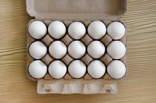 Directly above eggs in the egg carton on the wood background