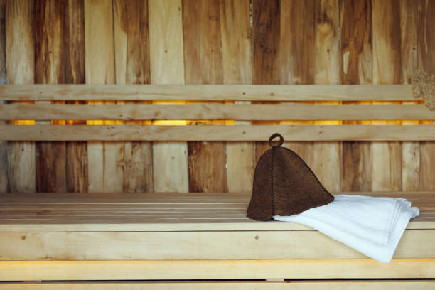 サウナの木の厚板からベンチに横たわるバスハットと白いタオル - サウナ ストックフォトと画像