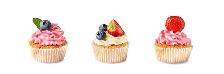 Collection of isolated cupcakes with cream and berries on a white background